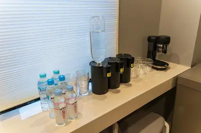 a counter with bottles of water and glasses on it at Business Hotel Kankokukan in Tokyo