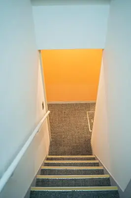 a staircase in an office with an orange and yellow wall at Business Hotel Kankokukan in Tokyo