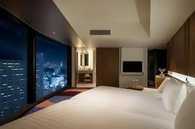 a hotel room with a large bed and a city skyline at HOTEL GROOVE SHINJUKU, A PARKROYAL Hotel in Tokyo