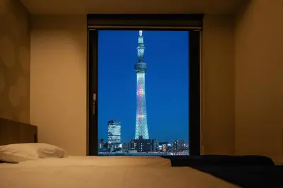 a view of the tokyo tower from a bedroom window at stayme THE HOTEL\u6d45\u8349\u30ea\u30d0\u30fc\u30b5\u30a4\u30c9 in Tokyo