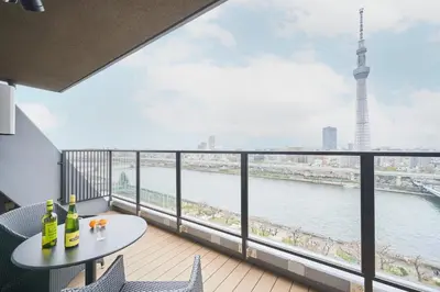 a balcony with a table and chairs and a view of a river at stayme THE HOTEL\u6d45\u8349\u30ea\u30d0\u30fc\u30b5\u30a4\u30c9 in Tokyo