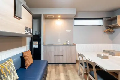 a kitchen and dining room with a blue couch and a table at stayme THE HOTEL\u4e0a\u91ce\u99c5\u524d in Tokyo