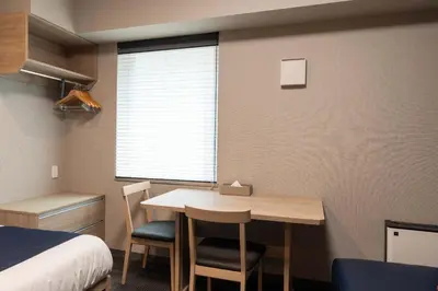 a small room with a table and chairs and a bed at stayme THE HOTEL\u4e0a\u91ce\u99c5\u524d in Tokyo
