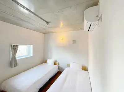 two beds in a room with white walls at PRISM Inn Komagata Asakusa in Tokyo