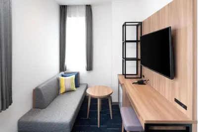 a hotel room with a couch and a tv on a wall at HOTEL MYSTAYS Nishi Shinjuku in Tokyo