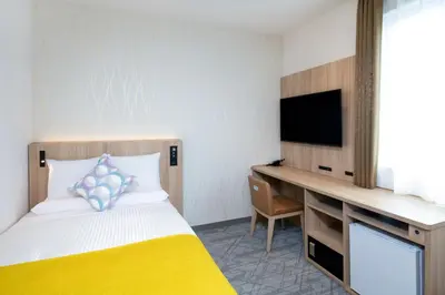a bedroom with a bed and a desk with a television at HOTEL MYSTAYS Nishi Shinjuku in Tokyo