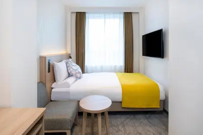a hotel room with a bed with a yellow blanket at HOTEL MYSTAYS Nishi Shinjuku in Tokyo