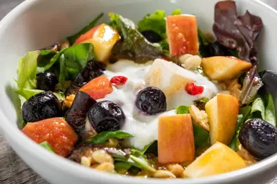 a salad with fruit and dressing in a white bowl at HOTEL MYSTAYS Nishi Shinjuku in Tokyo