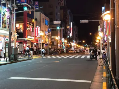 a city street at night with people riding bikes at \u685c\u306e\u5bbf28 square meter king size bed with sofa bed, garden room102 in Tokyo
