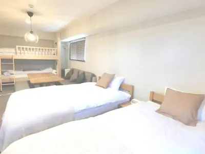a room with two beds and a table and a room with two beds at KLASSO Tokyo Sumiyoshi Apartments in Tokyo