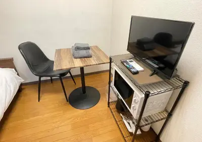 a room with a table with a chair and a tv at Beverly Homes Osaki by Tranova in Tokyo