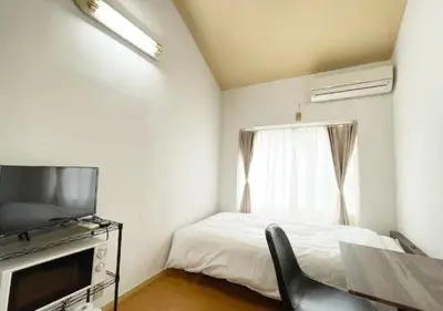 a bedroom with a bed and a television and a chair at Beverly Homes Osaki by Tranova in Tokyo