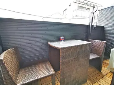 a patio with two chairs and a table and a wall at KIKI HOUSE \u65b0\u5c0f\u5ca9 in Tokyo