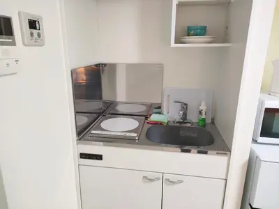 a small kitchen with a stove and a microwave at KIKI HOUSE \u65b0\u5c0f\u5ca9 in Tokyo