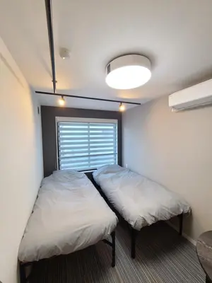 a small room with two beds and a window at \u30d1\u30fc\u30ea\u30fc\u30d5\u30e9\u30c3\u30c4\u54c1\u5ddd\u9ad8\u8f2a\u53f0 PEARLY FLATS Shinagawa Takanawadai in Tokyo