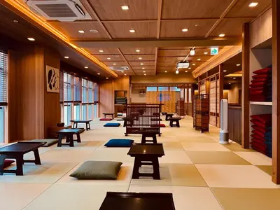 a lobby with tables and benches in a building at SPABLIC INN - Capsule Hatago Akasaka in Tokyo