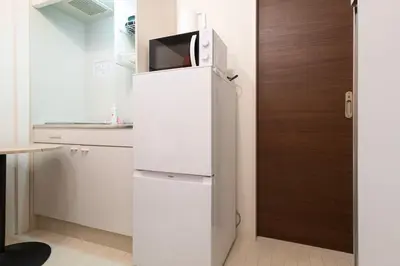a white refrigerator with a microwave on top of it at lON\u6e0b\u8c37\u672c\u753a in Tokyo