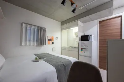 a bedroom with a white bed and a microwave at lON\u6e0b\u8c37\u672c\u753a in Tokyo