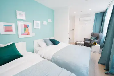a bedroom with two beds and a chair at Shinjuku Mermaid Apartment in Tokyo