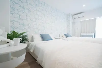 a bedroom with two white beds and a blue wall at Shinjuku Mermaid Apartment in Tokyo