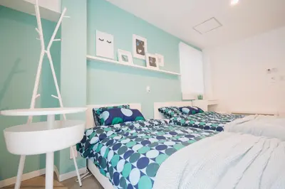 a bedroom with a bed and a white chair at Shinjuku Mermaid Apartment in Tokyo