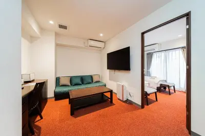 a living room with a green couch and a mirror at Serorin Light Hotel Tokyo in Tokyo