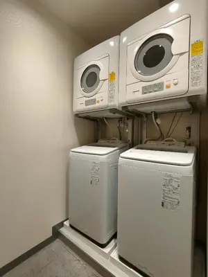 a laundry room with three washing machines and a microwave at Serorin Light Hotel Tokyo in Tokyo