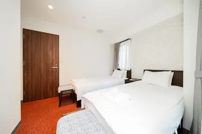 a hotel room with two beds and a door at Serorin Light Hotel Tokyo in Tokyo