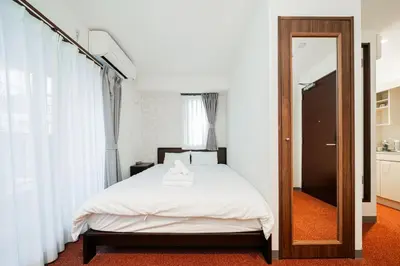 a bedroom with a white bed and a mirror at Serorin Light Hotel Tokyo in Tokyo