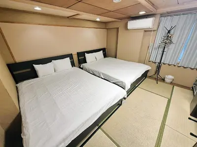 two beds in a small room with a window at Tokyo House INN in Tokyo