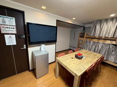 a room with a table and a flat screen tv at Tokyo House INN in Tokyo