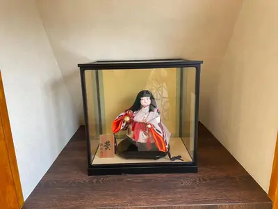 a doll in a glass box on a shelf at \u65b0\u5bbf\u3078\u884c\u304f\u4fbf\u5229\u306e\u4e00\u8ed2\u5bb6 in Tokyo