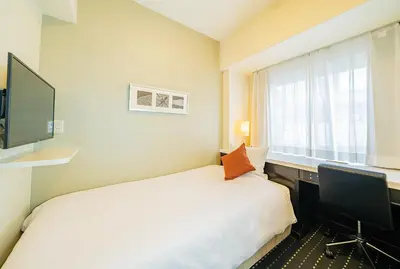 a bedroom with a bed and a desk with a computer at Kanda Station Hotel in Tokyo