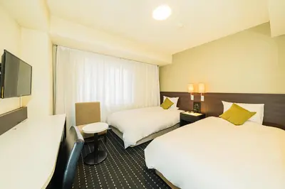 a hotel room with two beds and a flat screen tv at Kanda Station Hotel in Tokyo