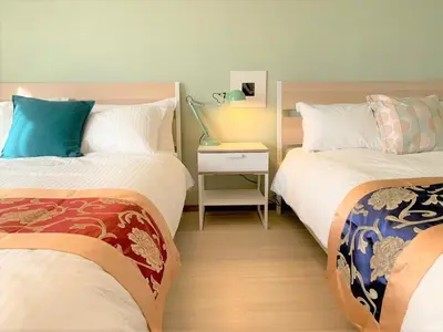 a room with two beds and a night stand with a bedskirts at Autumn Apartment Shinjuku in Tokyo