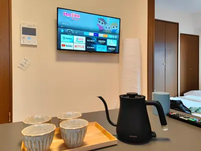 a coffeemaker on a table with three cups at ASAKUSA\u30fcHANAKAWADO in Tokyo