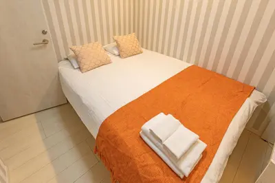 a small bedroom with a bed with an orange and white blanket at KOSUMOSU Ikebukuro Shinjuku Private House in Tokyo