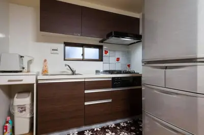a kitchen with wooden cabinets and stainless steel appliances at Mochida's Guest House in Tokyo