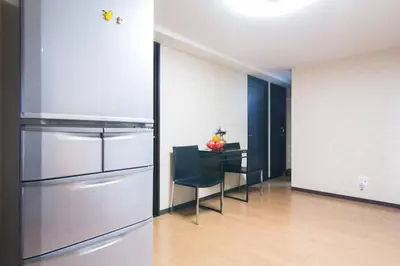 a kitchen with a refrigerator and a table with a chair at Mochida's Guest House in Tokyo