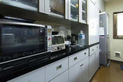a kitchen with white cabinets and a microwave oven at Mochida's Guest House in Tokyo