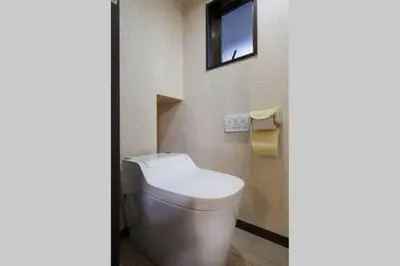 a bathroom with a toilet with a television on the wall at Mochida's Guest House in Tokyo