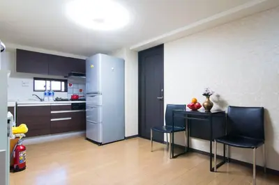 a kitchen with a table and chairs and a refrigerator at Mochida's Guest House in Tokyo