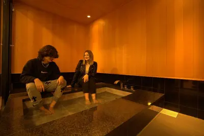 a man and a woman sitting on a sink in a bathroom at COGO Ryogoku in Tokyo