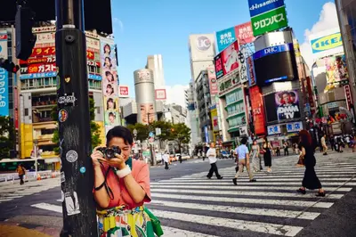 a woman taking a picture of a street with a camera at Hotel Indigo Tokyo Shibuya in Tokyo