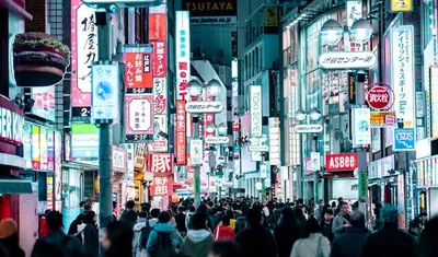 a crowd of people walking down a city street with signs at Hotel Indigo Tokyo Shibuya in Tokyo