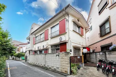 a building with red windows and bikes parked on the street at Wabi Sabi Hostel in Tokyo