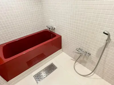 a red bath tub in a white tiled bathroom at HOTEL PARK SIDE in Tokyo