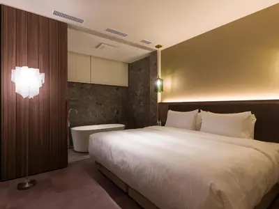 a bedroom with a large bed and a bath tub at THE skM TOKYO HOTEL & DINING in Tokyo