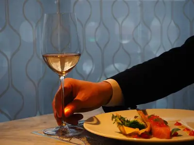 a person holding a glass of wine next to a plate of food at THE skM TOKYO HOTEL & DINING in Tokyo