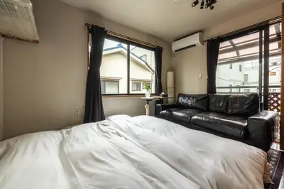 a bedroom with a bed and a leather couch at \u30a2\u30f3\u30c9\u30b9\u30c6\u30a4\u897f\u65b0\u4e95 in Tokyo